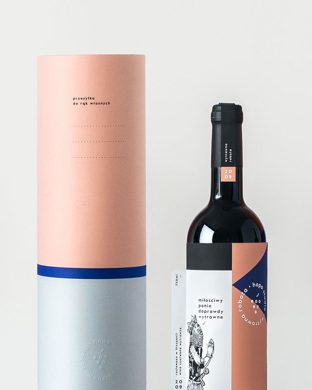 one paper tube packaging with a pink and white label with a bottle of wine next to it